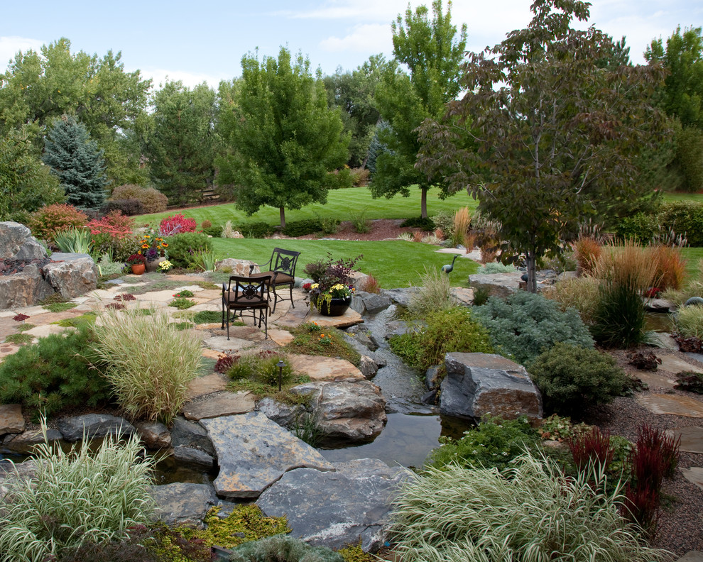 Diseño de jardín rural de tamaño medio en patio trasero con jardín francés, fuente y adoquines de piedra natural