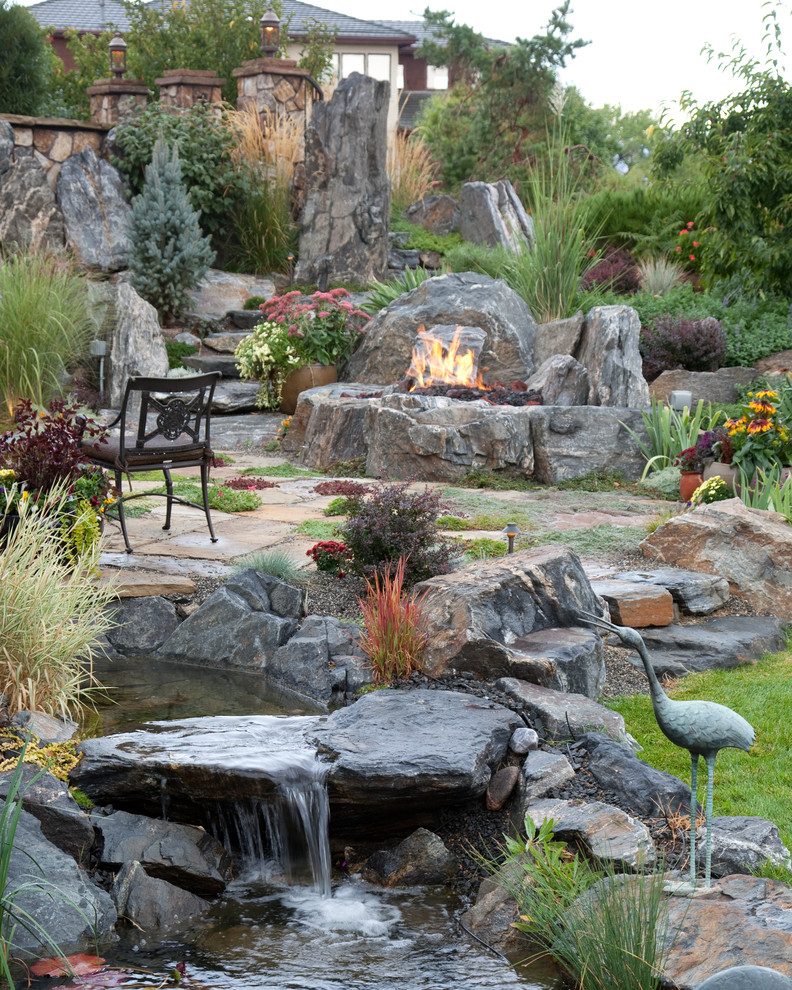 Modelo de jardín mediterráneo de tamaño medio en patio trasero con adoquines de piedra natural, jardín francés, fuente y exposición total al sol