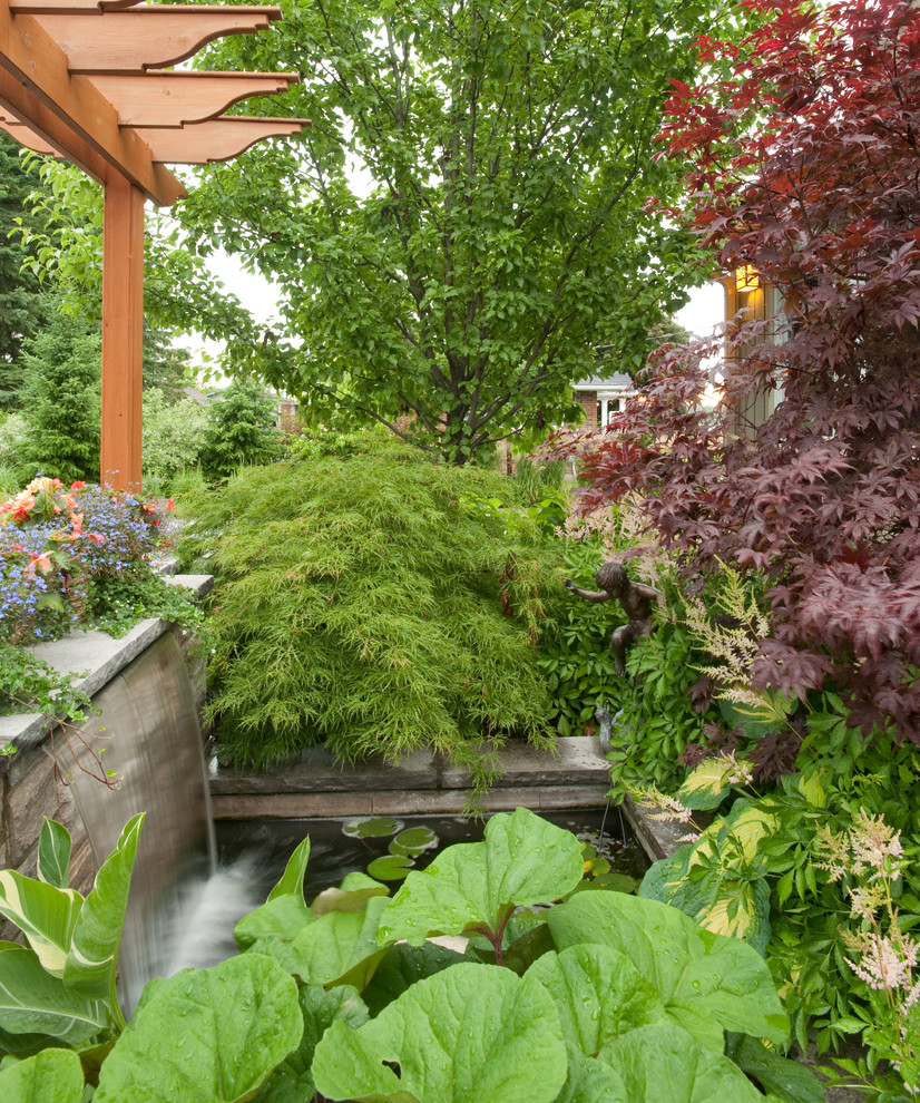 Imagen de jardín tradicional renovado en patio con fuente y adoquines de piedra natural