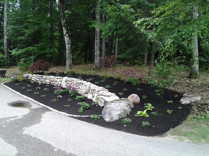 Photo of a medium sized country front partial sun garden in Portland Maine with a retaining wall and natural stone paving.