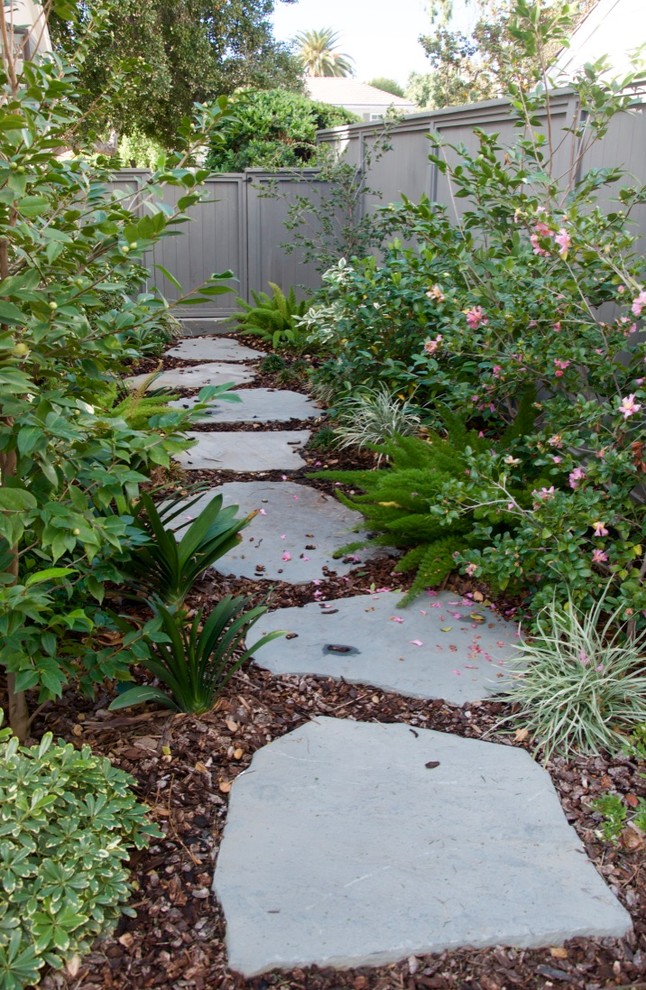 This is an example of a large side xeriscape fully shaded garden for spring in Los Angeles with a garden path and natural stone paving.