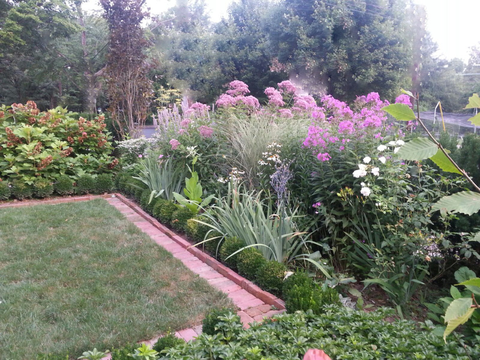 This is an example of a medium sized traditional front full sun garden for summer in DC Metro with a garden path.