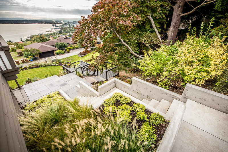 Esempio di un giardino contemporaneo dietro casa con un muro di contenimento e pavimentazioni in cemento