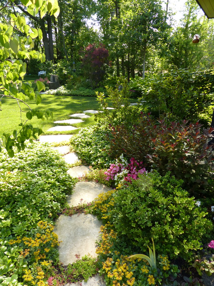 Exempel på en mycket stor klassisk bakgård i skuggan på våren, med en trädgårdsgång och naturstensplattor