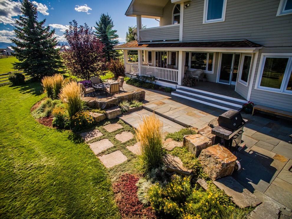 Foto di un grande giardino american style esposto in pieno sole dietro casa in autunno con un muro di contenimento e pavimentazioni in pietra naturale