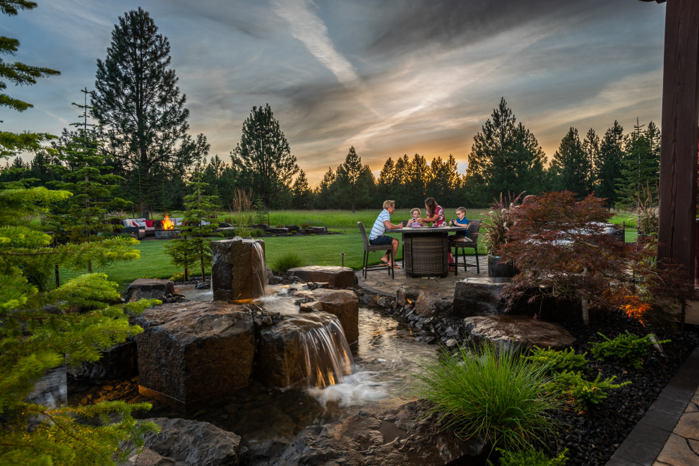 Großer Klassischer Garten hinter dem Haus mit Feuerstelle, direkter Sonneneinstrahlung und Natursteinplatten in Seattle