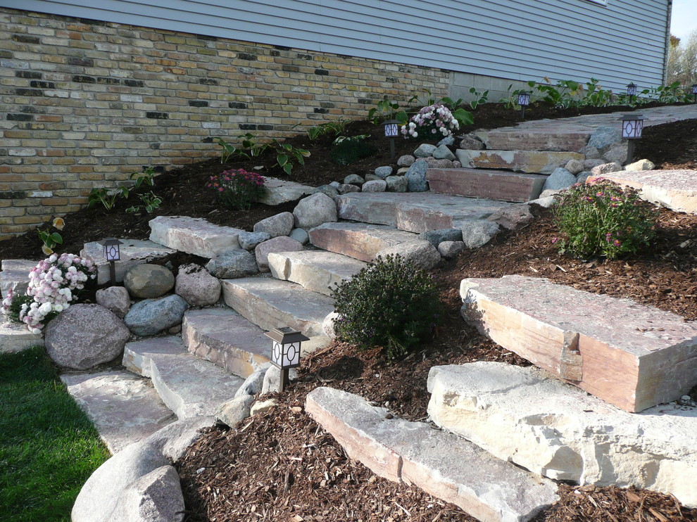 Réalisation d'un très grand jardin à la française chalet avec un mur de soutènement, une exposition ensoleillée, une pente, une colline ou un talus et des pavés en pierre naturelle.