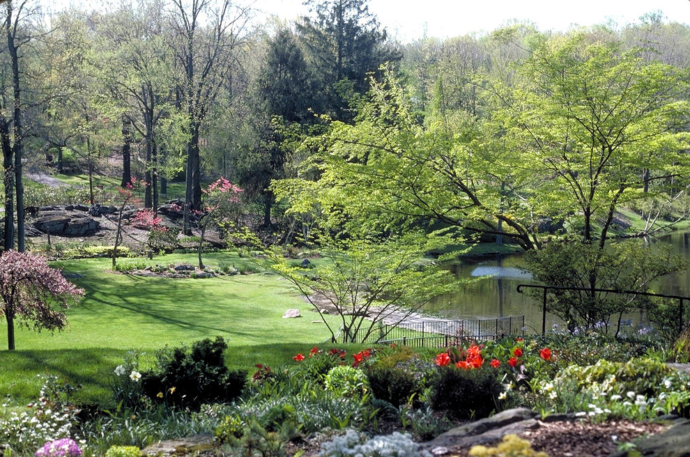 Foto di un ampio giardino classico esposto a mezz'ombra in primavera con un pendio, una collina o una riva