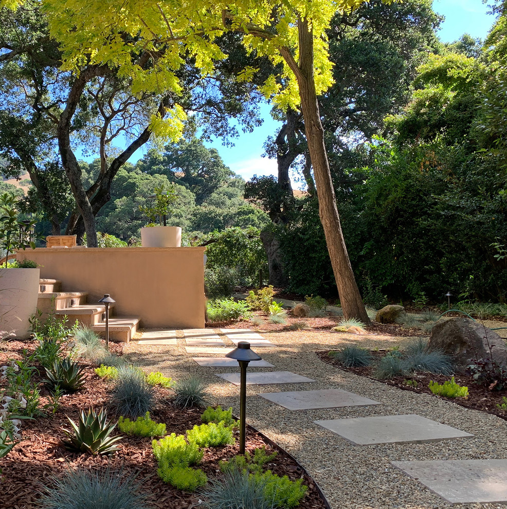 Aménagement d'un très grand jardin arrière contemporain l'été avec des pavés en pierre naturelle et une exposition partiellement ombragée.