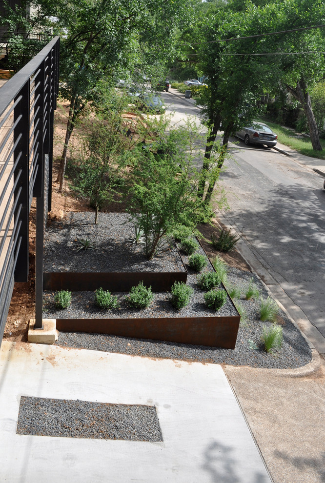 Design ideas for a large contemporary drought-tolerant and partial sun front yard gravel retaining wall landscape in Austin.