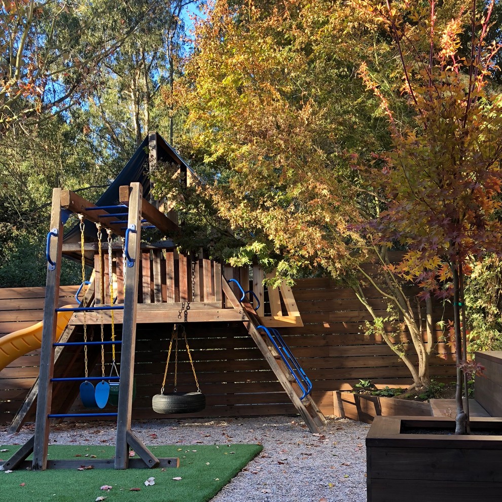 Ejemplo de jardín contemporáneo de tamaño medio en otoño en patio trasero con parque infantil, exposición parcial al sol y gravilla