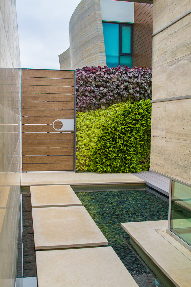 Halbschattiger Moderner Garten neben dem Haus mit Wasserspiel und Betonboden in Orange County