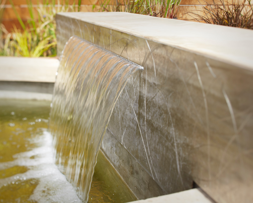 Foto di un giardino minimal di medie dimensioni con fontane, pavimentazioni in cemento e un pendio, una collina o una riva