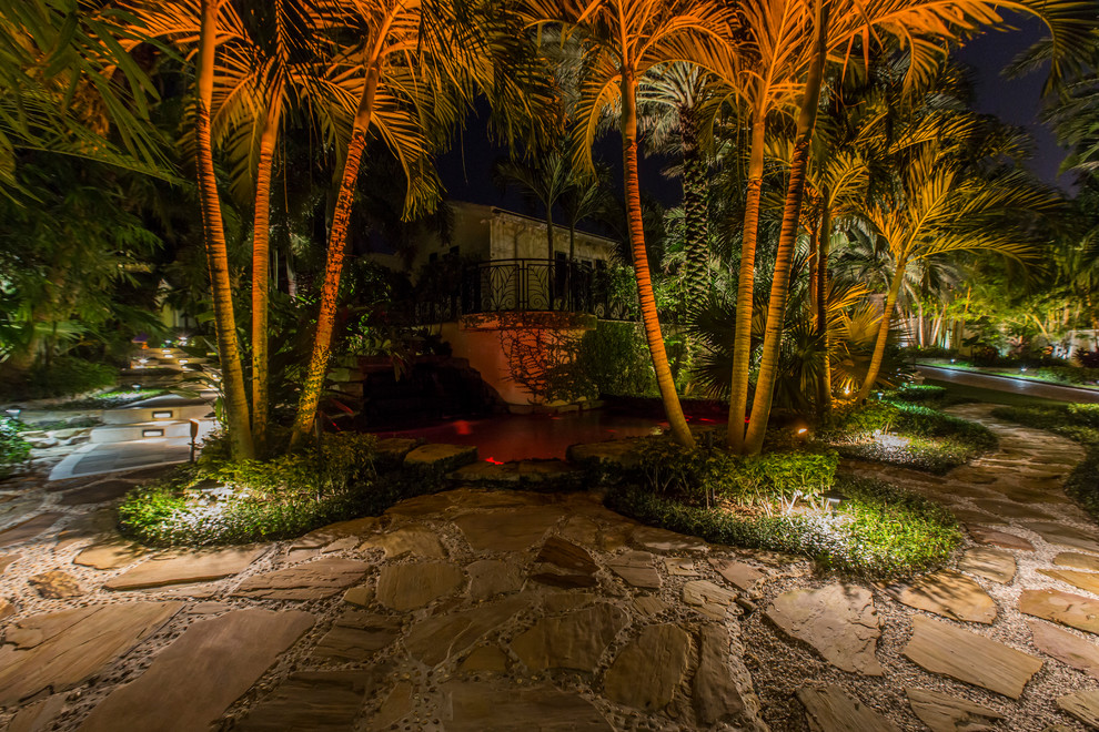 Foto di un ampio giardino formale tropicale esposto in pieno sole dietro casa in estate con fontane e pavimentazioni in pietra naturale