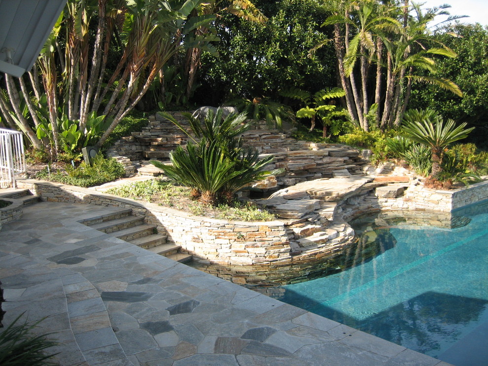 На фото: солнечный участок и сад среднего размера на заднем дворе в морском стиле с подпорной стенкой, хорошей освещенностью и покрытием из каменной брусчатки