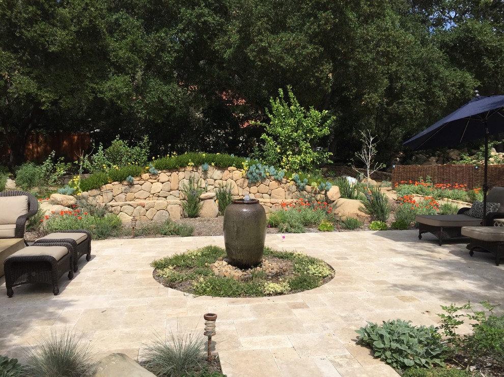 Modelo de jardín mediterráneo en patio trasero con fuente y adoquines de piedra natural