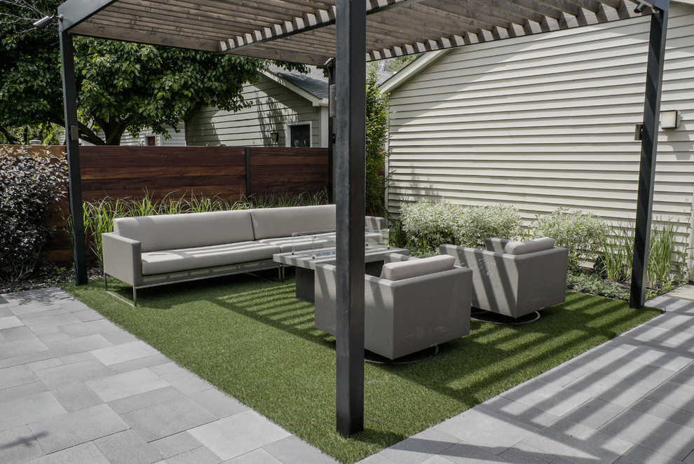 This is an example of a medium sized modern back partial sun garden for summer in Chicago with a fire feature and concrete paving.