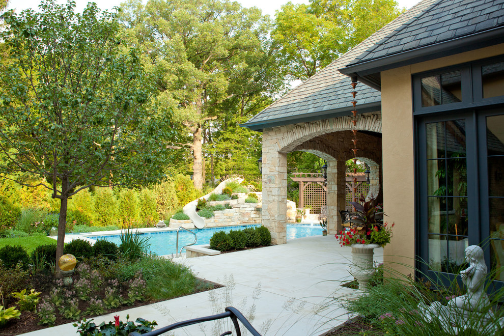 Diseño de jardín clásico en patio trasero con fuente y adoquines de piedra natural