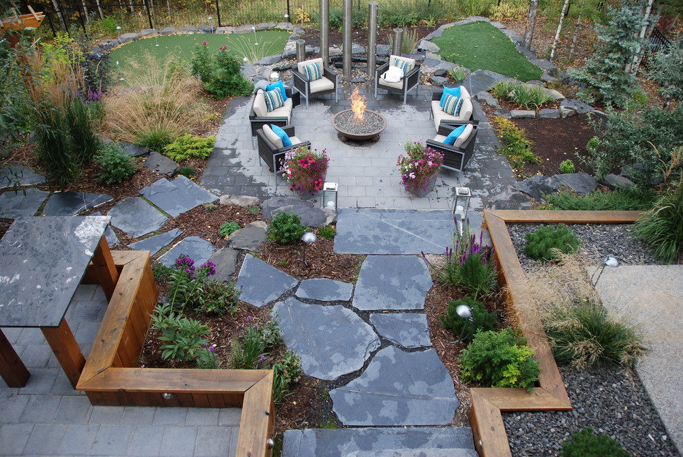 Стильный дизайн: огромный солнечный регулярный сад на заднем дворе в стиле модернизм с местом для костра, хорошей освещенностью и мощением клинкерной брусчаткой - последний тренд
