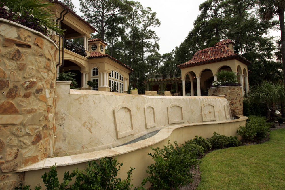 This is an example of a large mediterranean partial sun backyard stone water fountain landscape in Atlanta.