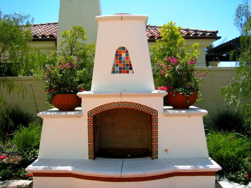 This is an example of a large mediterranean back formal garden in Orange County with concrete paving and a fireplace.
