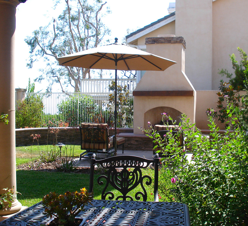 Mittelgroßer Mediterraner Gartenkamin hinter dem Haus mit direkter Sonneneinstrahlung und Betonboden in Orange County