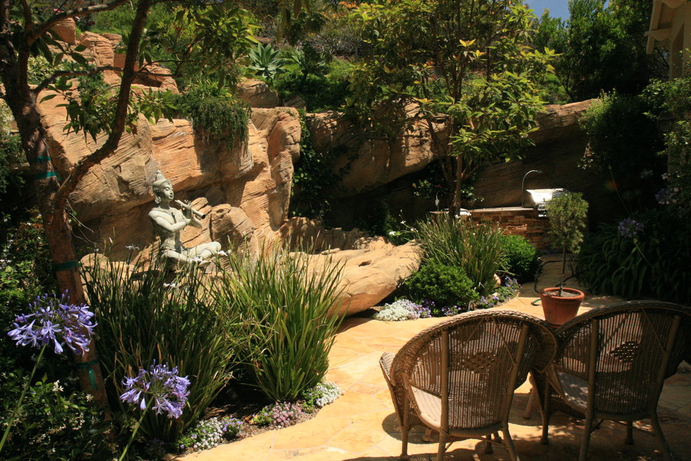 Imagen de jardín tropical en patio trasero con adoquines de piedra natural