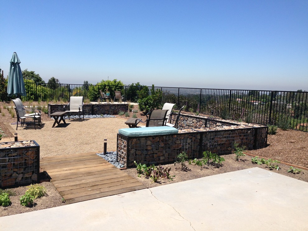 На фото: солнечный засухоустойчивый сад среднего размера на заднем дворе с хорошей освещенностью и покрытием из гравия