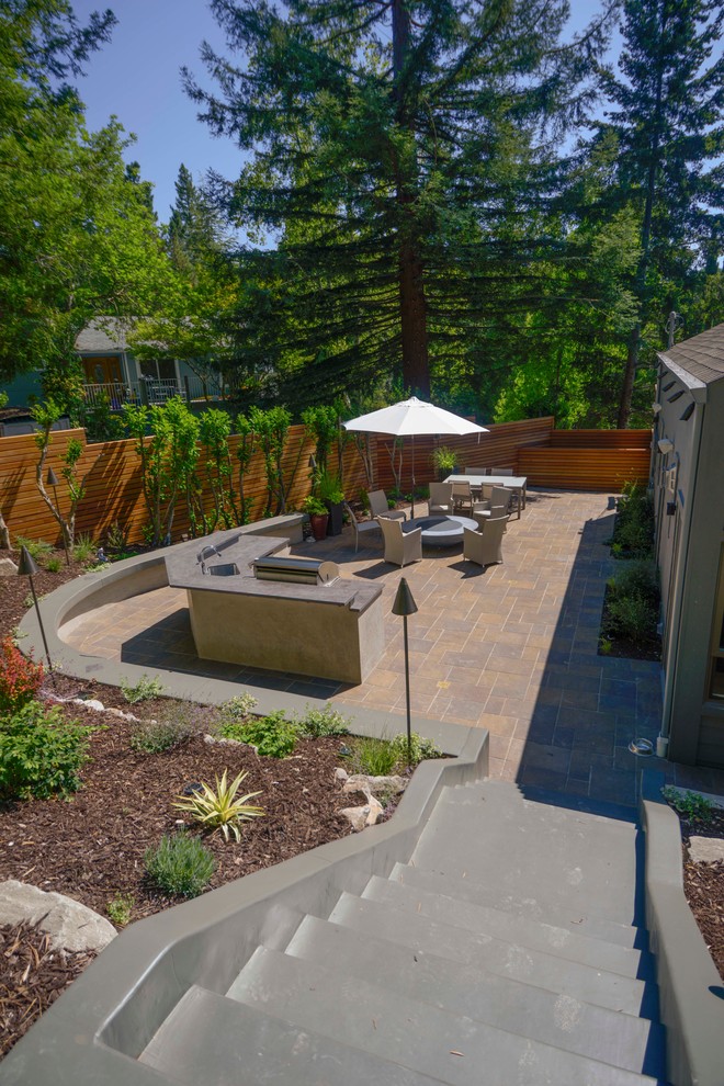 Foto de jardín minimalista de tamaño medio en patio lateral con brasero, exposición parcial al sol y adoquines de hormigón
