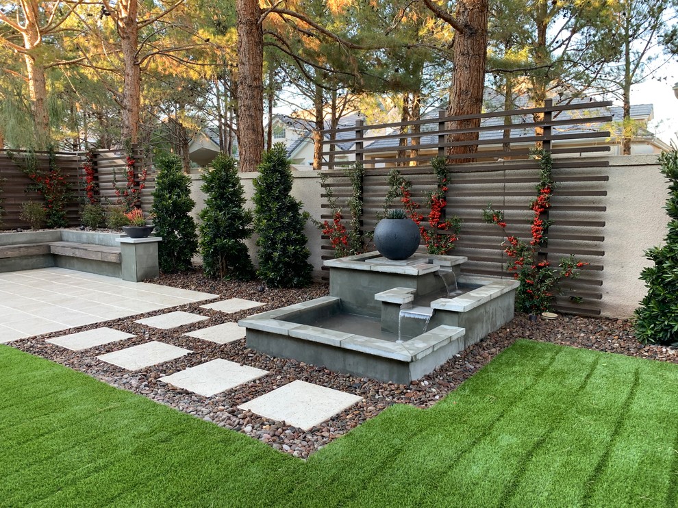 Ejemplo de jardín de secano minimalista de tamaño medio en patio trasero con exposición parcial al sol y adoquines de hormigón