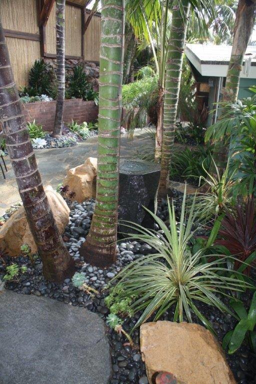 Modelo de jardín de secano costero de tamaño medio en verano en patio delantero con jardín vertical, exposición total al sol y adoquines de hormigón