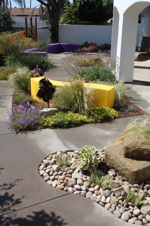 Modelo de jardín minimalista grande en primavera en patio trasero con jardín francés, brasero, exposición total al sol y adoquines de hormigón