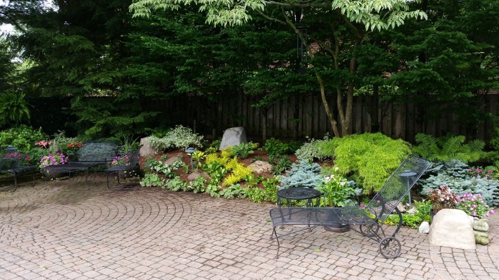 Foto de jardín clásico renovado de tamaño medio en patio trasero con exposición parcial al sol y adoquines de ladrillo