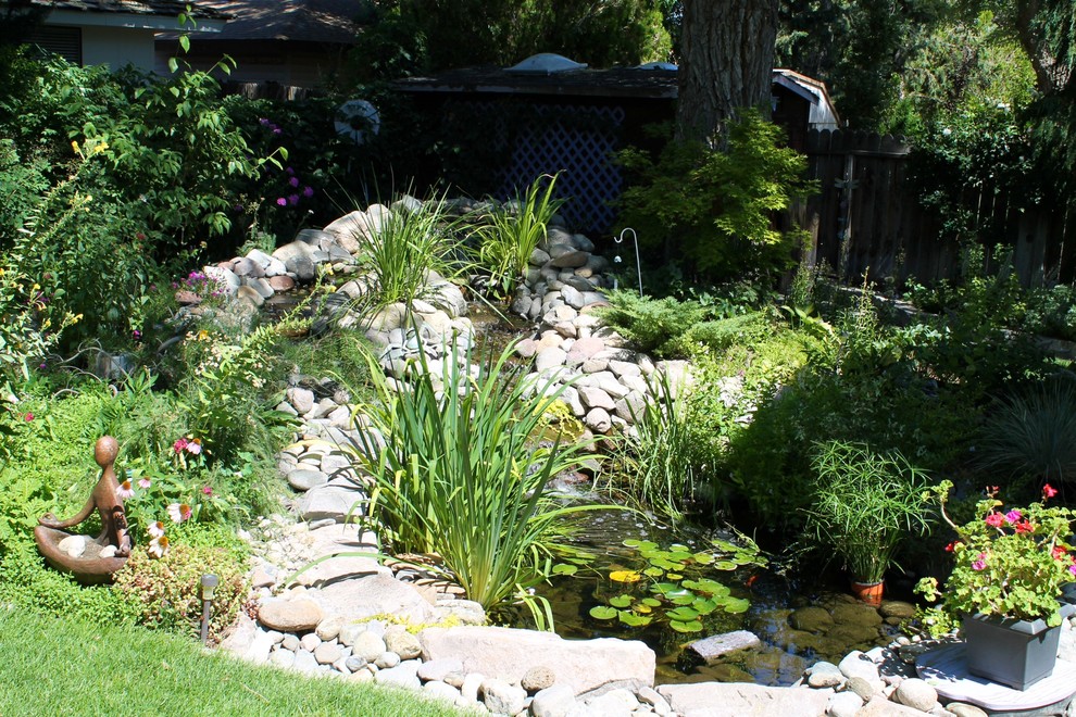 Mittelgroßer, Halbschattiger Klassischer Garten im Sommer, hinter dem Haus mit Wasserspiel und Natursteinplatten in Sonstige