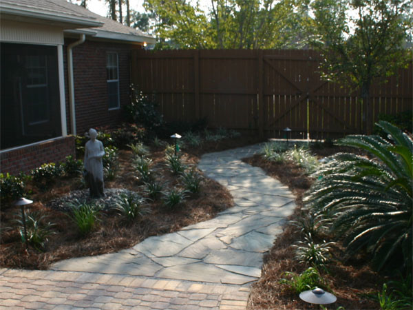 Photo of a tropical partial sun backyard concrete paver retaining wall landscape in Miami for summer.