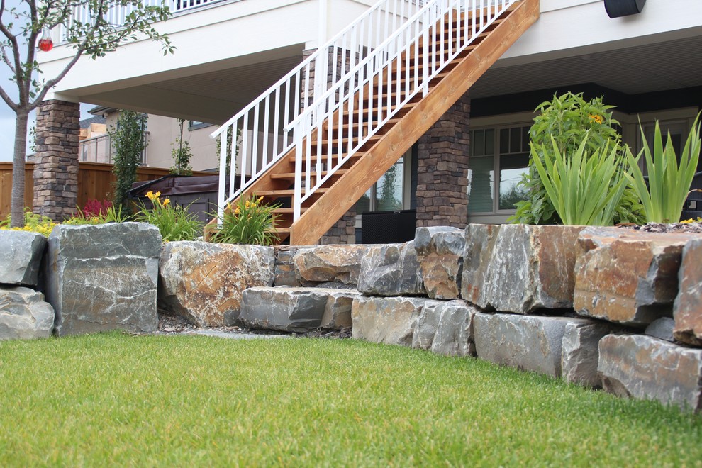 This is an example of a mid-sized rustic full sun backyard stone landscaping in Calgary.