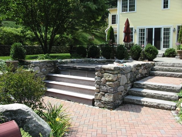 Medium sized classic sloped full sun garden in Louisville with a retaining wall and brick paving.