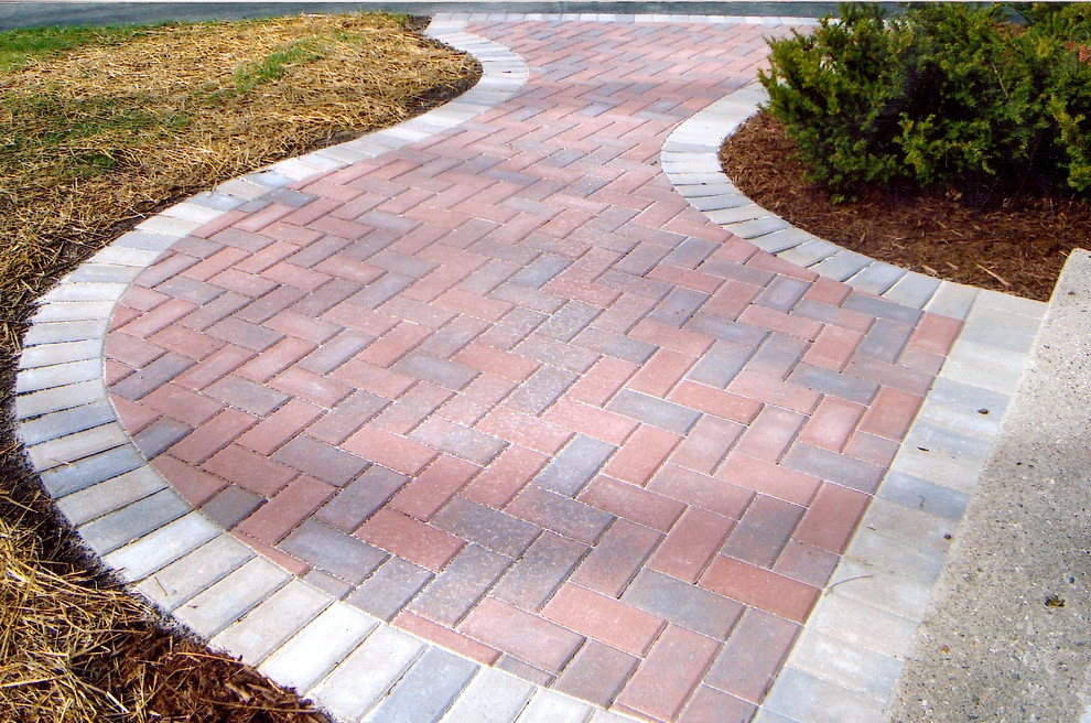 This is an example of a medium sized traditional front driveway garden in Other with brick paving.