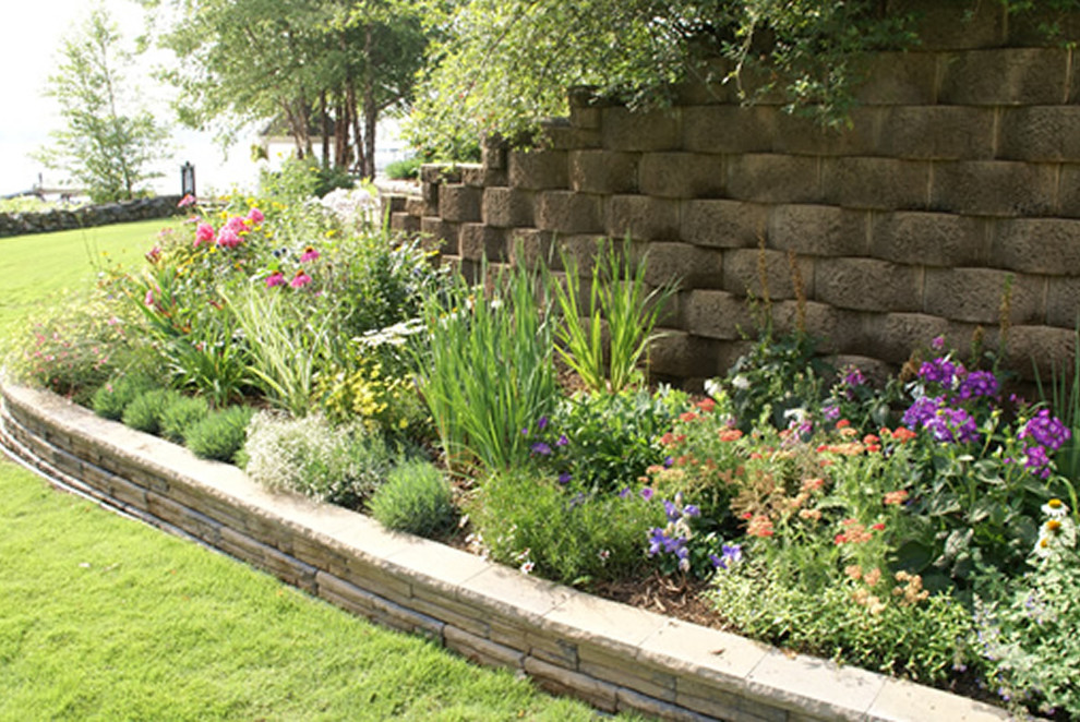 Imagen de jardín clásico de tamaño medio en patio trasero con muro de contención, exposición reducida al sol y adoquines de hormigón