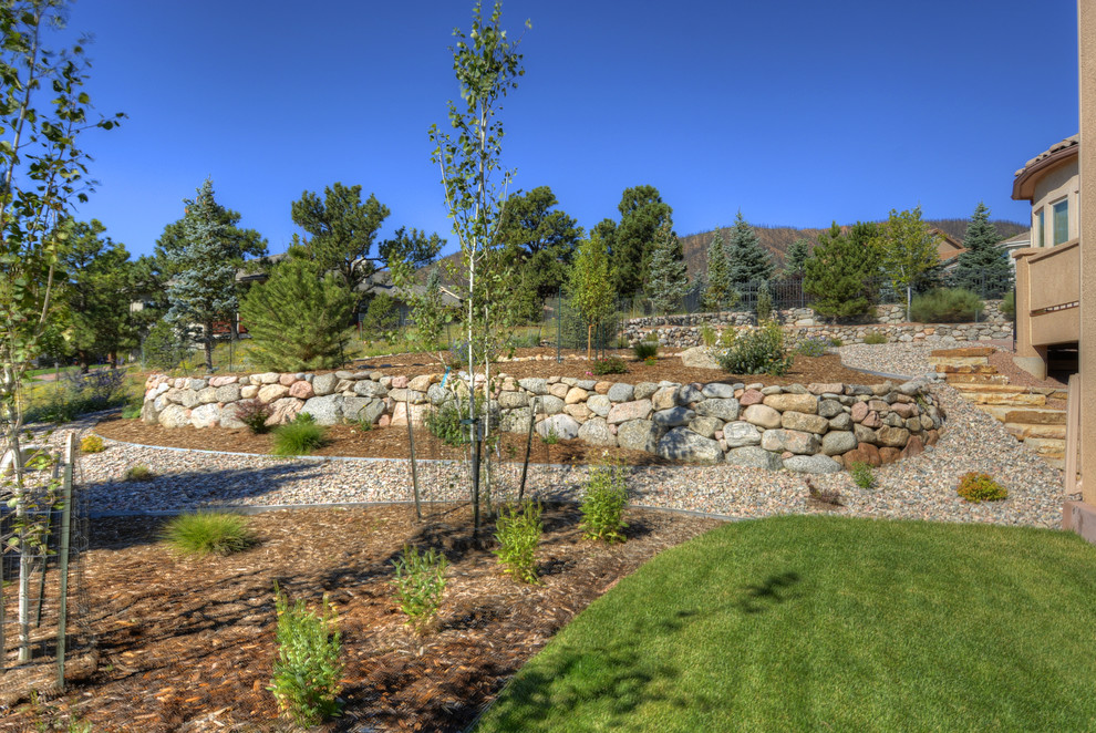 Inspiration for a traditional partial sun backyard retaining wall landscape in Denver.