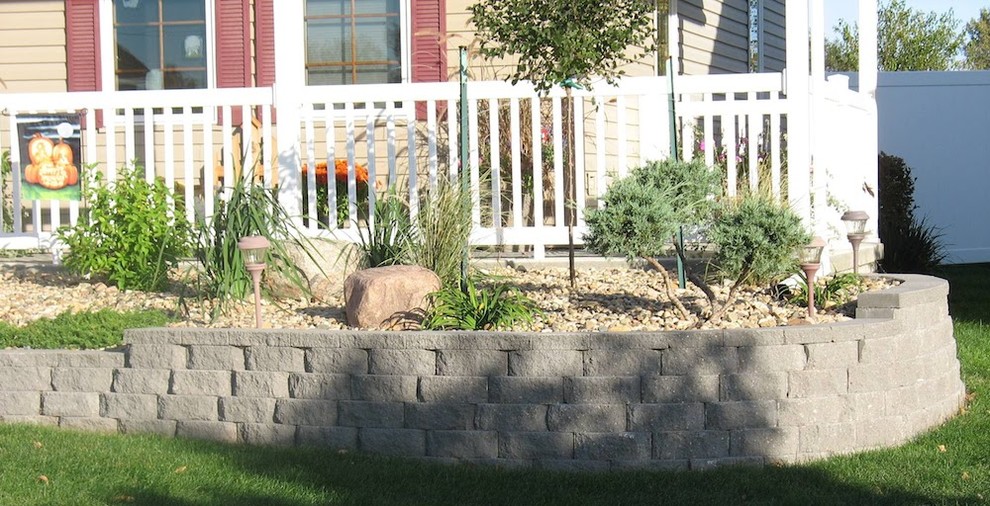Cette image montre un petit jardin avant traditionnel avec un mur de soutènement et des pavés en brique.