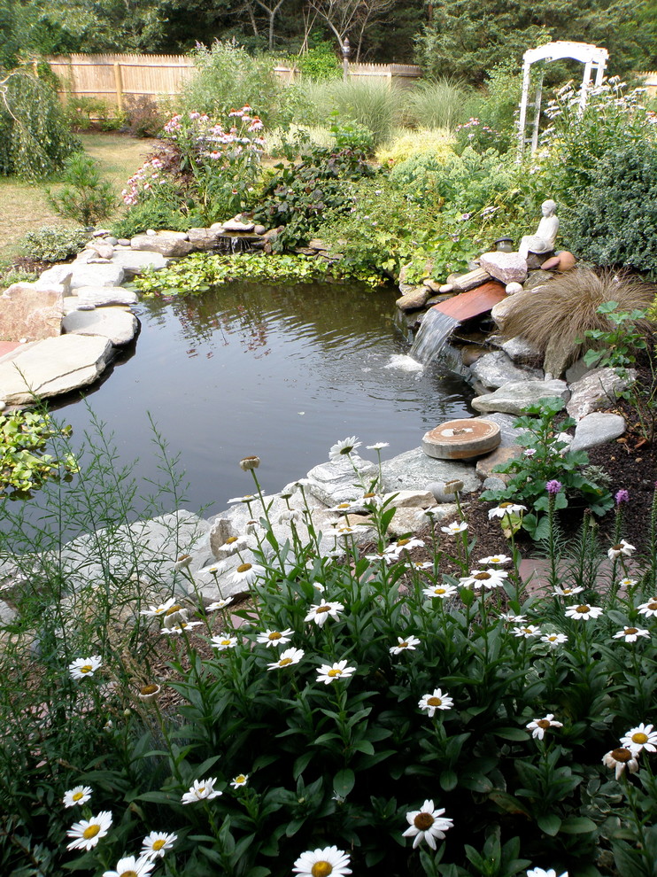 Design ideas for a medium sized world-inspired back formal partial sun garden for spring in Boston with a pond and natural stone paving.
