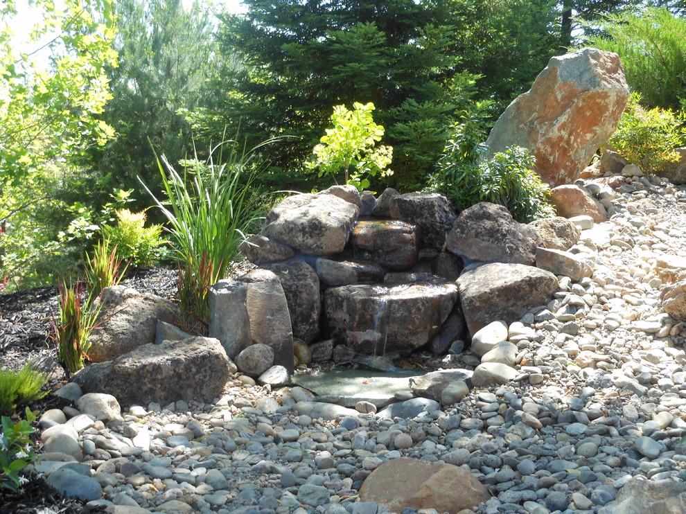 Uriger Garten hinter dem Haus mit Wasserspiel, direkter Sonneneinstrahlung und Natursteinplatten in Sacramento