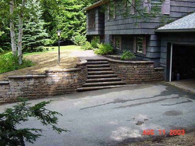 Modelo de acceso privado tradicional de tamaño medio en patio delantero con muro de contención y adoquines de piedra natural