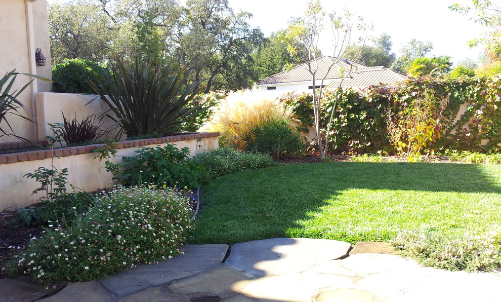 Foto de jardín clásico de tamaño medio en patio trasero con jardín francés, exposición total al sol y adoquines de piedra natural