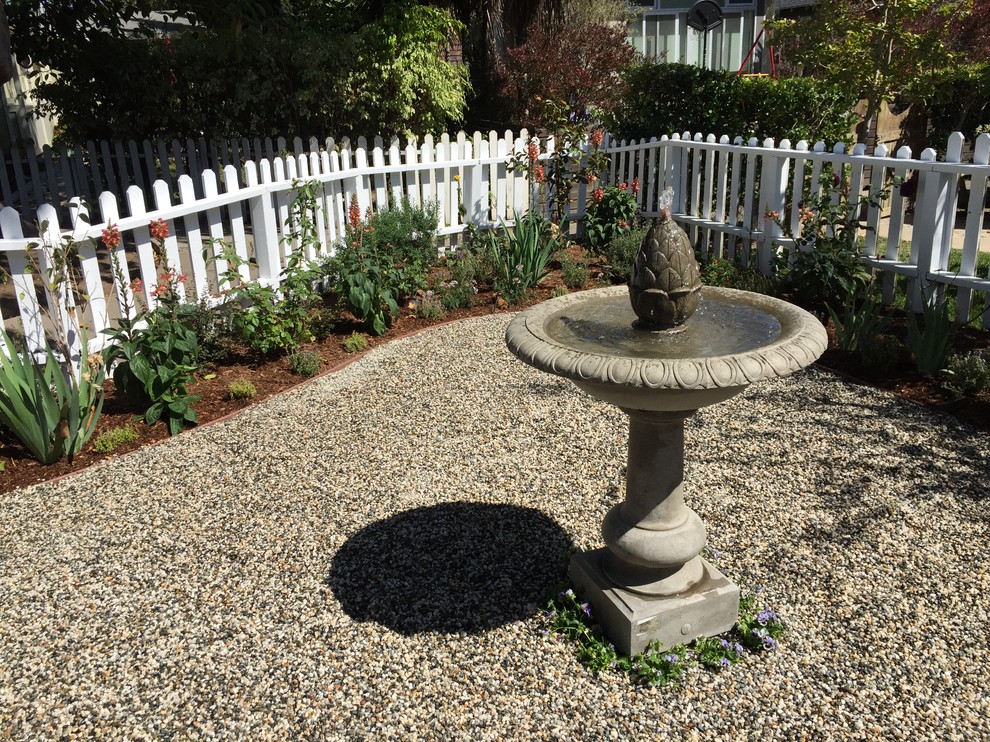 Modelo de jardín clásico de tamaño medio en primavera en patio trasero con jardín francés, fuente, exposición parcial al sol y gravilla