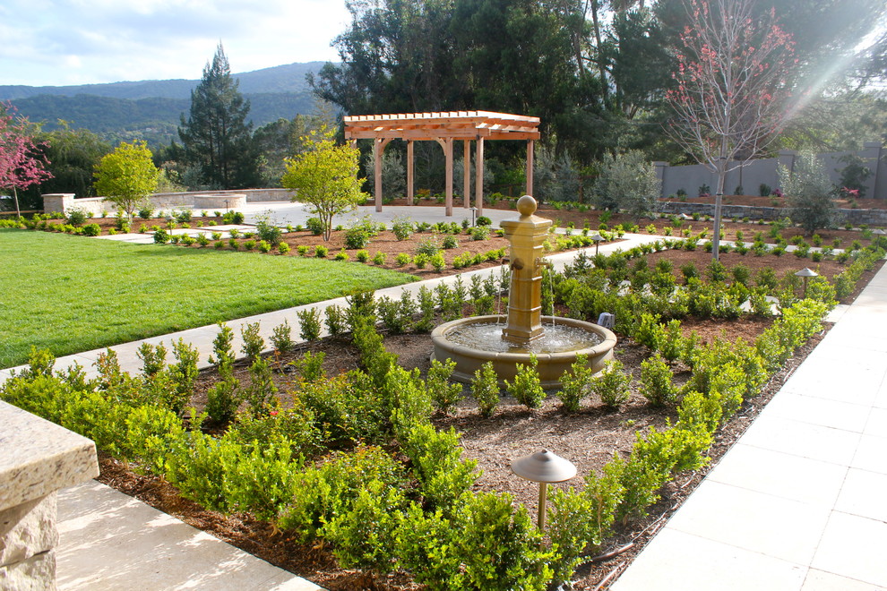 Diseño de jardín moderno extra grande en patio trasero con fuente, exposición total al sol y mantillo