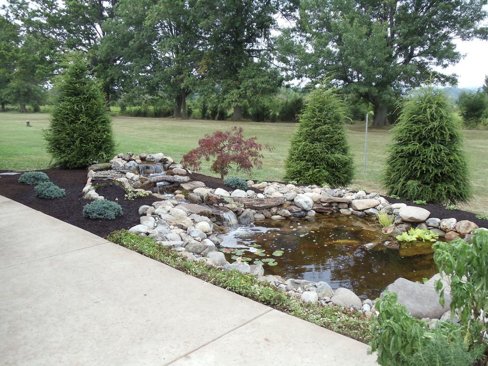 На фото: большой садовый фонтан на заднем дворе в современном стиле с покрытием из каменной брусчатки