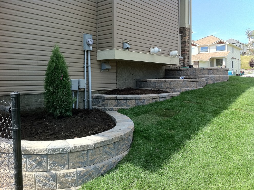 This is an example of a large classic side fully shaded garden in Calgary with a retaining wall and mulch.
