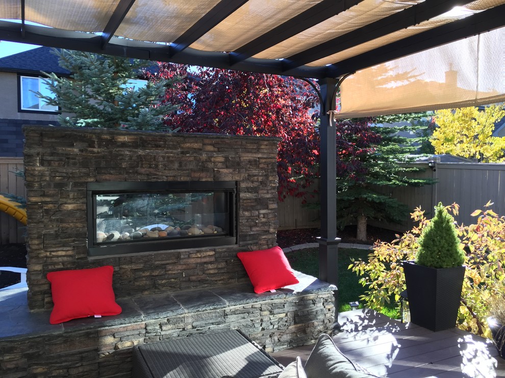 Kleiner Moderner Gartenkamin hinter dem Haus mit direkter Sonneneinstrahlung und Dielen in Calgary